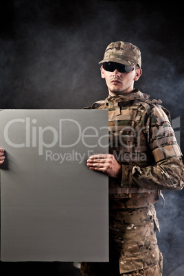 Modern soldier is holding a poster