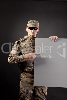 Modern soldier is holding a poster