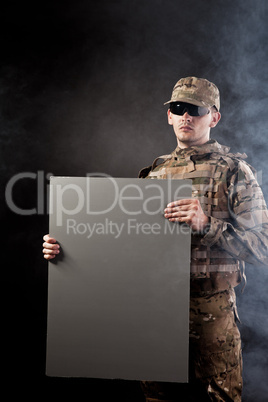 Modern soldier is holding a poster