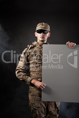 Modern soldier is holding a poster