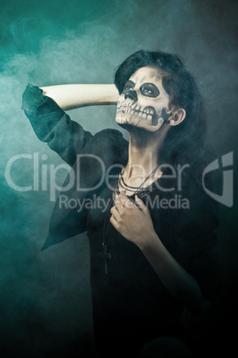 Young woman in day of the dead mask skull face art. Halloween face art with fog