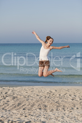 Fröhliche Frau springt lachend am Starnd Hochformat