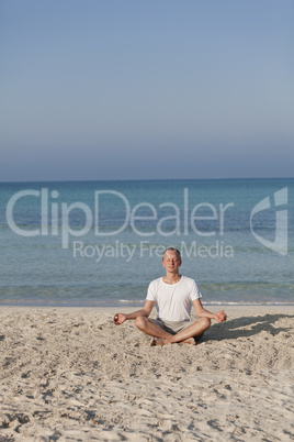 Mann macht yoga Sport am Strand Hochformat