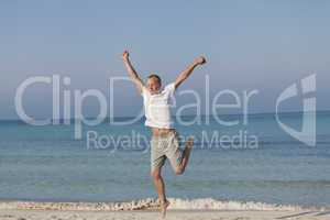 Fröhlicher Mann springt lachend am Strand Querformat