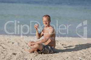 Mann trinkt wasser aus einer flasche am Strand Querformat