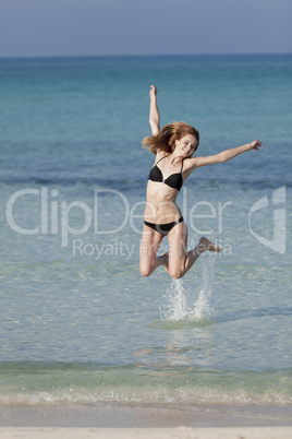 Frau mit Bikini springt im meer hochformat