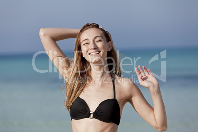 Junge Frau mit Bikini lachend am Strand Portrait Querformat