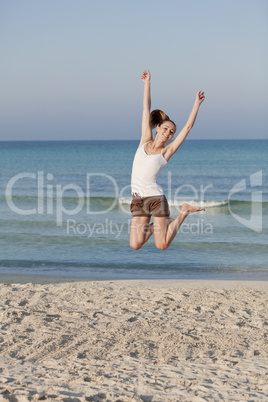 Fröhliche Frau springt lachend am Starnd Hochformat