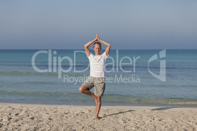 Mann macht yoga Sport am Strand Querformat