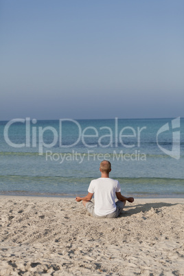 Mann macht yoga Sport am Strand Hochformat