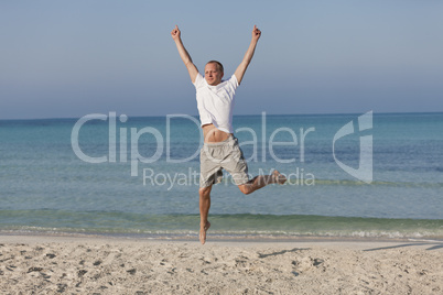 Fröhlicher Mann springt lachend am Strand Querformat