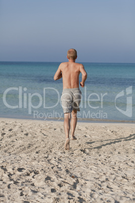 mann rennt am strand im Wasser Hochformat