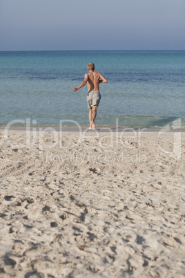 mann rennt am strand im Wasser Hochformat