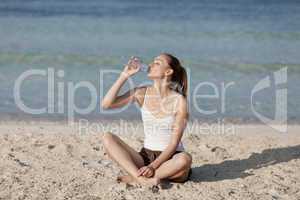 Frau trinkt wasser aus einer flasche am Strand Querformat
