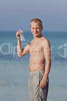 Mann trinkt wasser aus einer flasche am Strand Hochformat