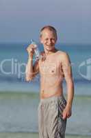 Mann trinkt wasser aus einer flasche am Strand Hochformat