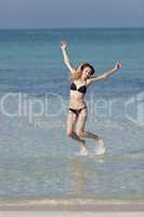 Frau mit Bikini springt im meer hochformat