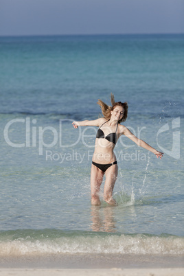 Frau mit Bikini springt im meer hochformat