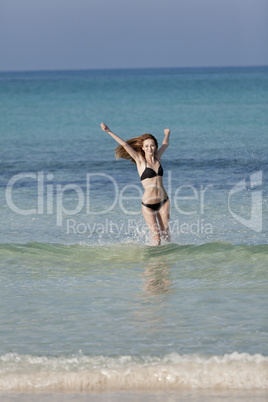 Frau mit Bikini im meer beim Springen Hochformat