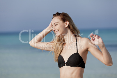 Junge Frau mit Bikini lachend am Strand Portrait Querformat