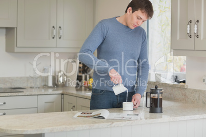 Man pouring milk into coffee