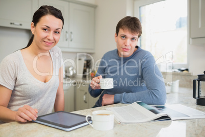 Smiling woman with tablet pc and man with newspaper