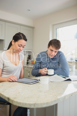 Two people reading from tablet pc and magazine