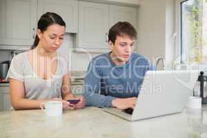 Woman on smartphone with man on laptop