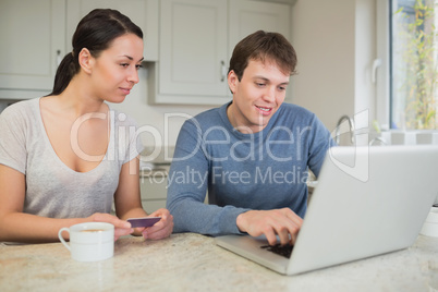 Man showing woman something on laptop