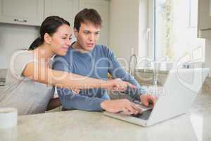 Young couple seeing something interesting on laptop