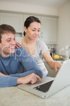 Smiling young couple using laptop