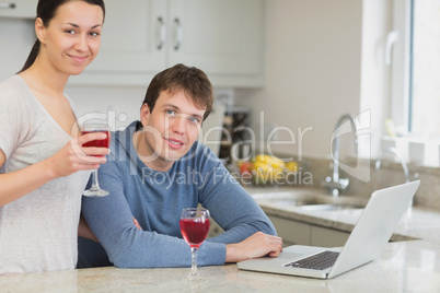 Young couple using laptop drinking red wine