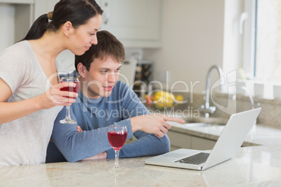 Couple drinking red wine and using laptop