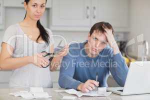 Disappointed couple in the kitchen cutting credit card