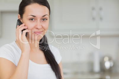 Woman using the mobile phone in the kitchen