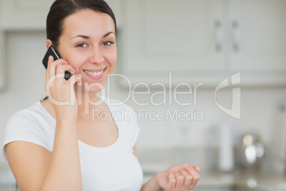 Woman calling with the mobile phone in the kitchen