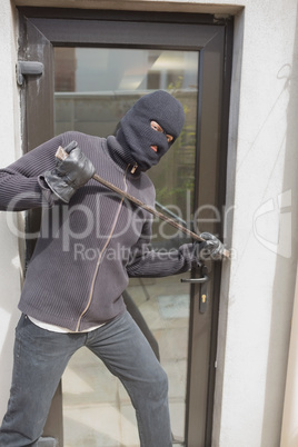 Burglar breaking into home using crow bar