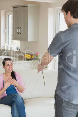 Woman sitting on the couch getting a flower