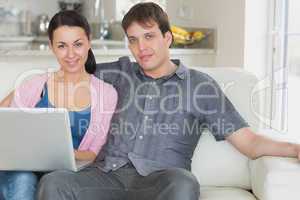 Two people relaxing while using the laptop