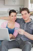 Two people using the laptop on the couch