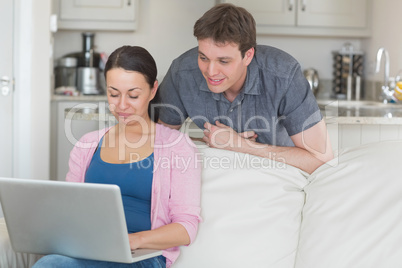 Woman using laptop with man looking on