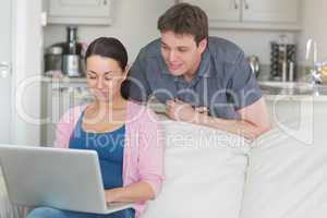 Woman using laptop with man looking on