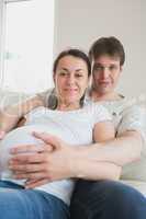 Pregnant woman lying on couch with partner