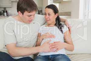 Surprised couple feeling baby kicking in mother's belly