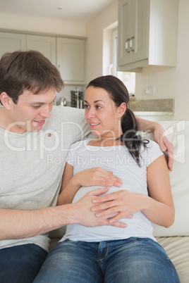 Pregnant woman sitting on the couch with her partner