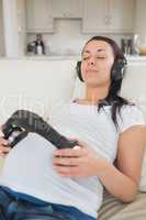 Pregnant woman listening to music and holding headphones on bell