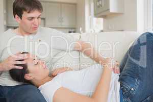 Pregnant woman resting on husband on sofa