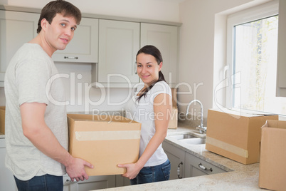 Young couple in the kitchen holding moving boxes