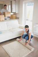 Woman laying out rug with man holding moving boxes