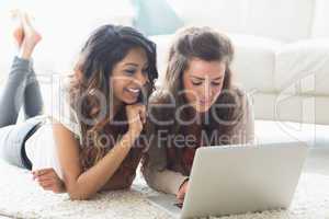 Smiling women lying on the floor with a computer